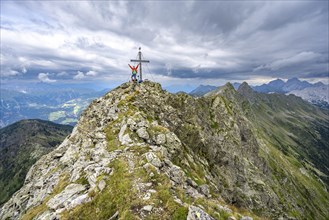 Mountaineer stretches his arms in the air, on the rocky pointed summit of the Raudenspitze or Monte