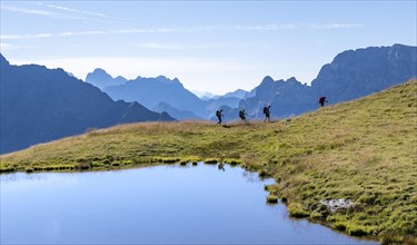 Group of mountaineers in front of mountain landscape, mountain lake and silhouettes of rocky