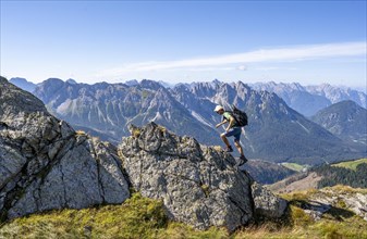 Mountaineer on a rocky ridge in front of a mountain panorama, view of the mountain peaks of Cresta