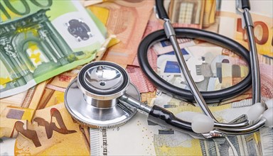 Symbolic photo of medical expenses, a stethoscope and medical instruments on a surface of euro