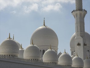 Close-up of the large domes and minaret of an impressive mosque against a bright sky, large mosque