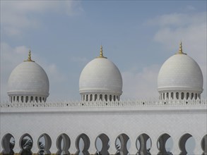 Three big white domes of a mosque with blue sky and a few clouds, big mosque with white domes and
