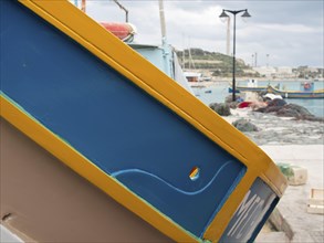 Close-up of a colourful boat in the harbour with a view of the landscape in the background, many