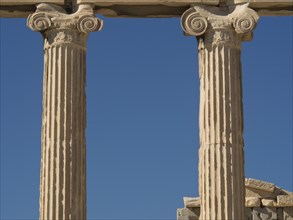 Close-up of ancient marble columns and their details against a clear blue sky, historical columns