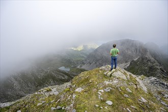 Mountaineer on the summit of the Pfannspitze or Cima Vanscuro, cloudy mountain peaks, Carnic Main