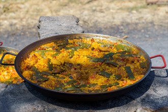 Close-up of a typical Spanish paella cooked over a wood fire in the countryside
