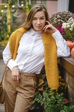 Outdoor portrait of cute lovely woman at an autumn fair leaning on a wooden display table