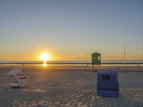 Beach at sunset with two beach chairs and a calm sea coast, beautiful sunset on the beach of an