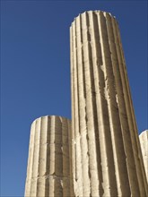 Detailed close-up of tall ancient columns under clear sky, historical columns and ruins at an