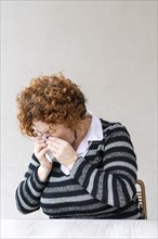 Side view of a woman blowing her nose