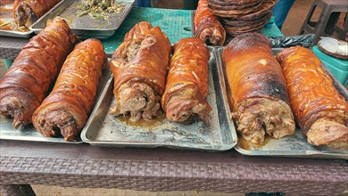 Rows of golden brown roasted pork belly or lechon liempo displayed at a street market showing an