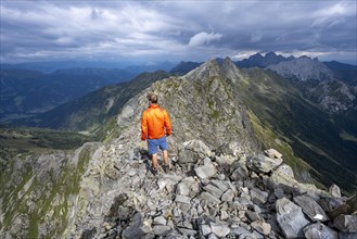 Mountaineer on the rocky pointed summit of the Raudenspitze or Monte Fleons, view of narrow