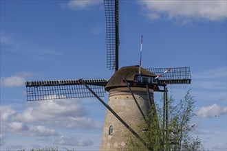 Historic windmill under a blue sky with white clouds, many historic windmills on a river in the