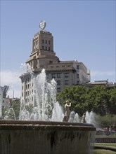 A fountain with statues and water fountains in front of a historic building under a clear sky,