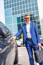 Vertical photo of a cool businessman next to his luxury car about to leave after work in the