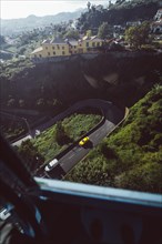 Yellow car on a winding road in a mountainous urban landscape. Madeira, Portugal, Europe