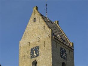Brick church tower with two clock faces and blue sky in the background, church tower on stone with