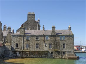 Historic stone houses on the shore with water and sea, blue sky, old stone house directly on the