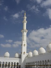 Islamic mosque with minaret, white domes and golden decorations under a blue sky, beautiful mosque