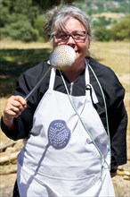 Woman cook in white apron with a spatula in her hand smiling in the field