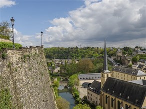 Landscape view with a church, city wall, river and hills under a cloudy sky in springtime, old