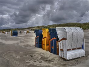 A composition of beach chairs in cloudy weather in a dune landscape, colourful beach chairs on the
