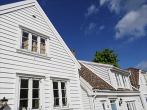 White wooden houses with windows and gutters under a clear blue sky in the sunshine, white wooden