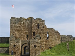 Close-up of a castle ruin with medieval architecture and a flag in the wind under a blue sky, ruins