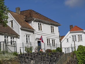 White wooden houses with red tiled roofs and norwegian flag in the foreground of a sunny day, white