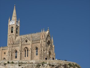 Historic gothic-style church with a tall bell tower under a blue sky, stand-alone church on an