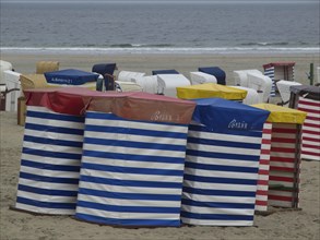 Row of colourful beach chairs with stripe pattern on the beach with a view of the sea, beach chairs