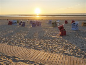 Colourful beach chairs on the beach at sunset, calm atmosphere and golden hour over calm sea,