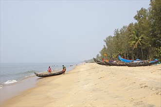 Indian fishermen pushing their boat into the sea, colourful fishing boats on the beach, Cherai