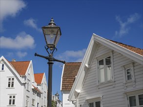 Streetlamp with white houses in the background, red roofs under clear sky, white wooden houses with