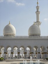Elegant mosque with striking white domes and a high minaret under a clear sky, beautiful mosque