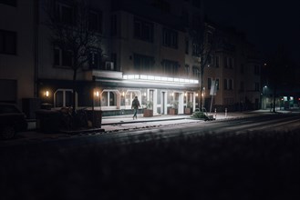 Lonely man walks towards the darkness. Illuminated by the light of the hotel. Taken at night in