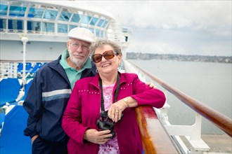 Senior adult couple enjoying the view from their passenger cruise ship with their bonoculars
