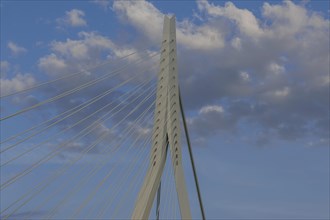 Close-up of a modern bridge with ropes and minimalist design under a cloudy sky, skyline of a