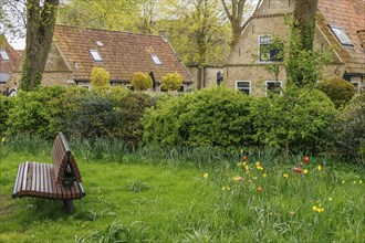 Villagers enjoy the spring colours and tranquillity in a lush green park, old houses with green