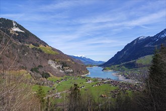 View of a valley with a lake and a village surrounded by mountains under a blue sky, Lungern,