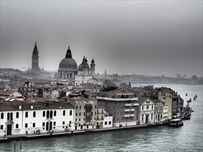 Foggy view of Venice's historic building line along the canal, church towers and historic buildings