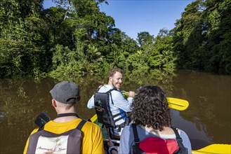 Tourists in a rowing boat on the Tortuguero River, watching animals in the rainforest, Tortuguero