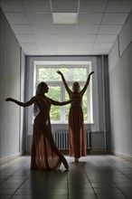 Silhouette of two female dancers rehearsing choreography in the hallway of theatre