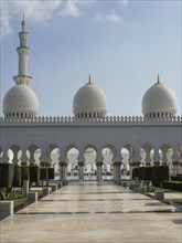 Large mosque with striking white domes and detailed architecture under a clear sky, beautiful