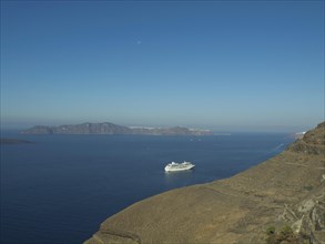 A cruise ship sailing on clear blue sea surrounded by islands and blue sky, rocky island in the sea