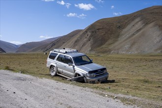 Broken-down off-road vehicle with broken axle on the side of the road, Karkyra Valley, Karkyra