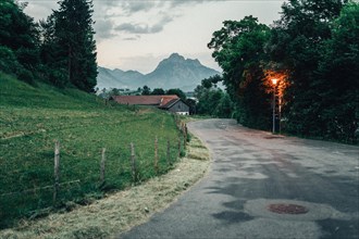 A rural road winds through a picturesque landscape at sunset. Lake Hopfensee, Bavaria Germany