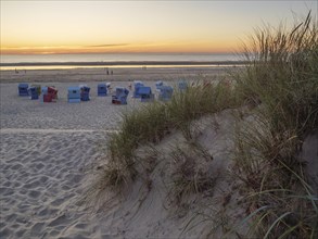 A quiet beach at sunset with a view of beach chairs, dunes and the sea, Sunset on a beach with