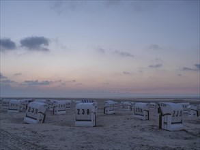 Empty beach chairs at sunset on a quiet beach with cloudy sky, setting sun on a beach with beach