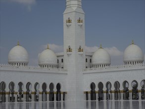 Magnificent mosque with white domes and a high minaret against a blue sky, beautiful mosque with